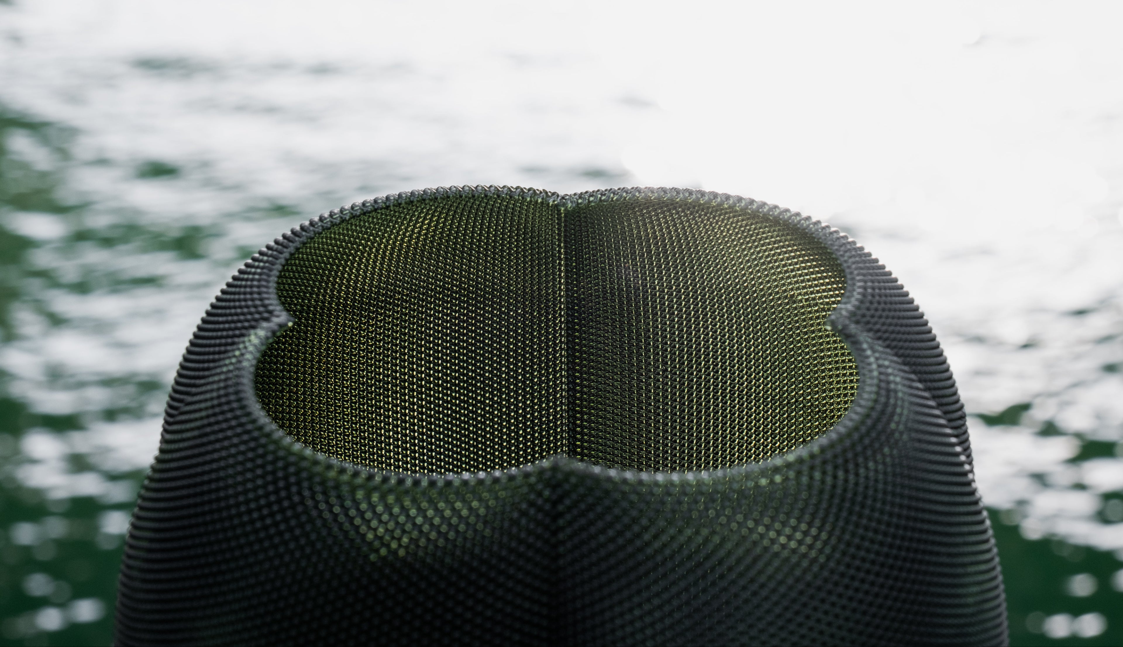 Close-up of a green mesh screen against a blurred water background